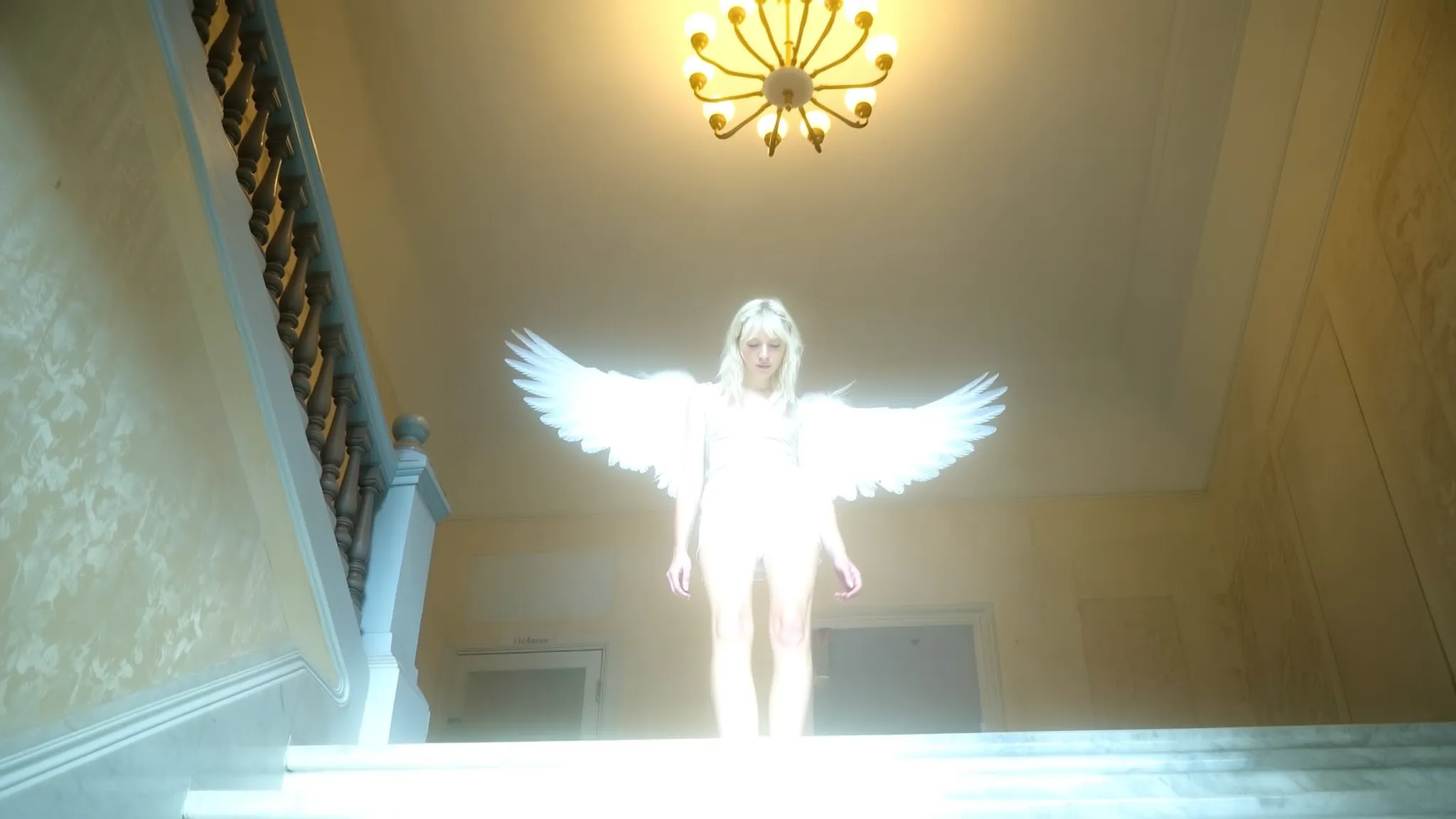 Captured from a low angle near the base of a marble staircase, the image centers on a platinum-blonde woman stepping upward. Both of her small to medium angel wings trail behind her, fully visible but softened by intense overexposure that dissolves feather detail. Her glowing figure bleaches the surrounding space, blurring into the faint glow of an underlit Haussmann apartment interior. The walls behind her reveal traces of faded wallpaper, textures diminished beneath a veil of ambient haze. Above, a large chandelier's blurred light contributes to the gentle flood of diffuse illumination. The framing is slightly off-center and tilted, giving the impression of a fleeting handheld capture. Her minimal clothing, rendered in washed pale tones, blends seamlessly into the quiet, suspended atmosphere of soft, diffuse glow. The entire scene holds a quiet, neutral mood—an ephemeral vision caught in a dim, overexposed urban interior.