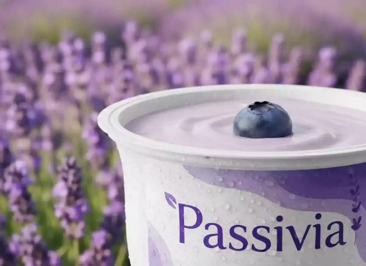 A hyperrealistic photo shows a close-up of a blueberry smoothly sinking into a container of creamy lavender-colored yogurt, highlighting detailed texture and soft ripples, suitable for ai image generator and product placement ai content.