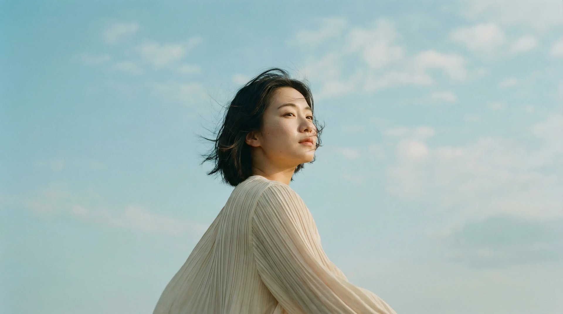 Creator wearing a sculptural pleated garment under a blue sky